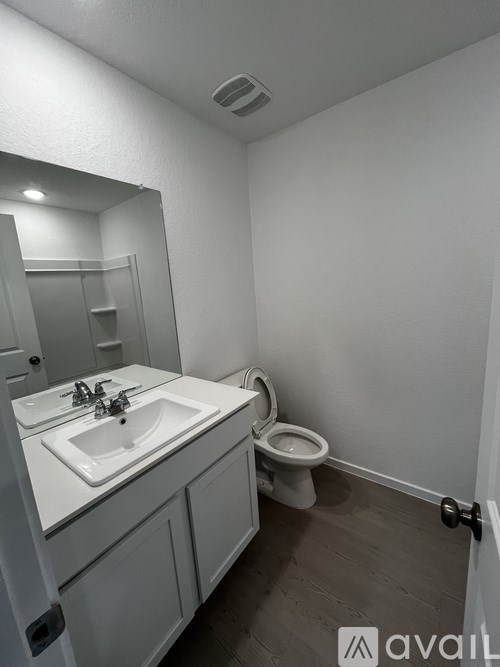 A bathroom with a toilet, sink, and mirror.