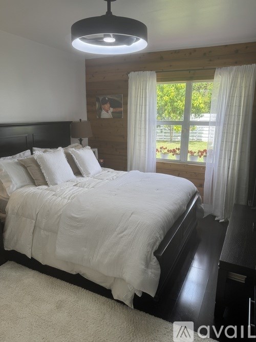 A bedroom with a large bed and a window overlooking a garden.