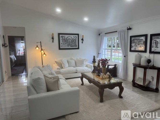 A living room with a white couch, a coffee table, and a painting on the wall.