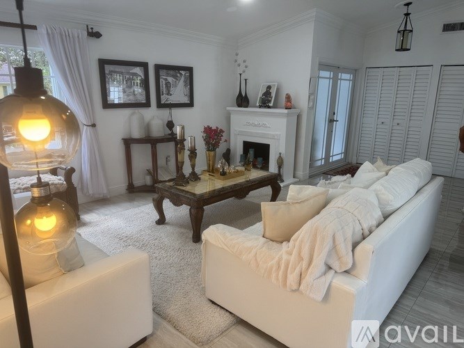 A living room with a white couch, a coffee table, and a fireplace.