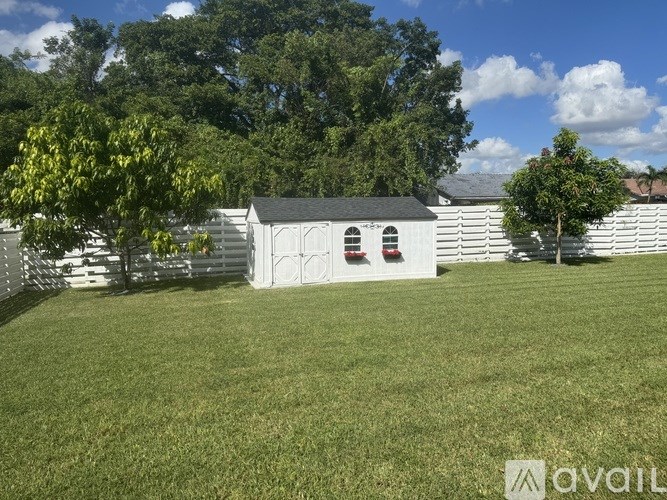 A white building with a black roof is surrounded by a grassy field.