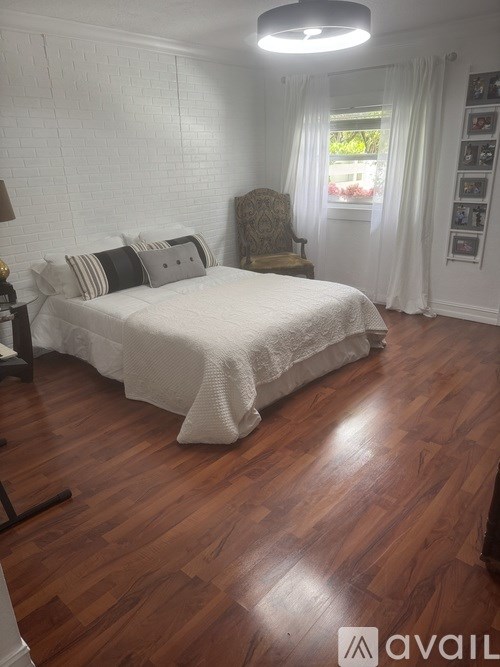 A white fence runs along a tree-lined street.