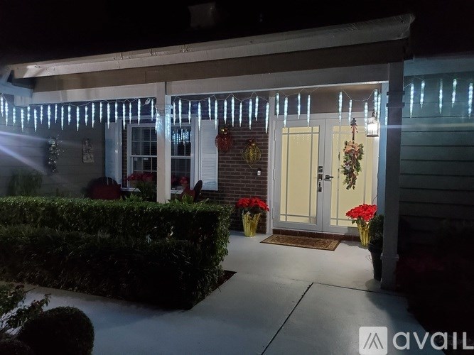A house entrance with a white door and a hedge on the left.