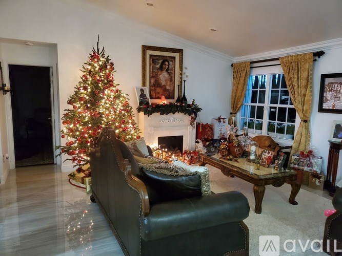 A living room decorated for Christmas with a tree, presents, and a fireplace.