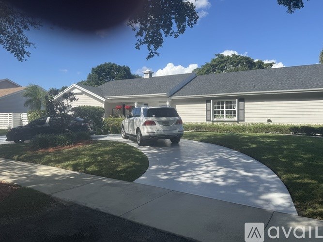 A silver car is parked on a driveway in front of a house.