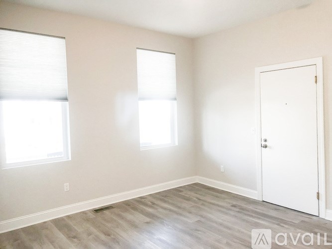 A room with a white door and two windows with blinds.