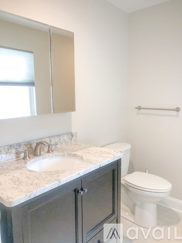 A bathroom with a sink, toilet and cabinets.