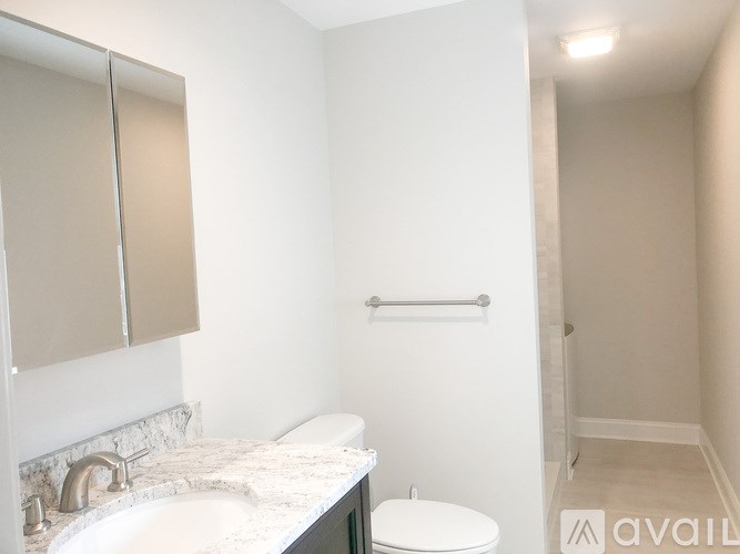 A bathroom with a sink, toilet and a towel bar.