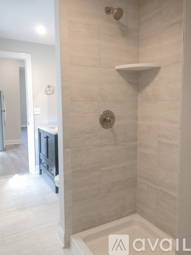 A bathroom with a walk in shower and a white bench.