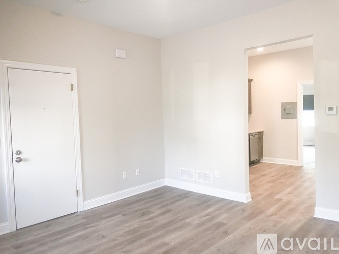A room with a white door and a white wall with a switchboard.