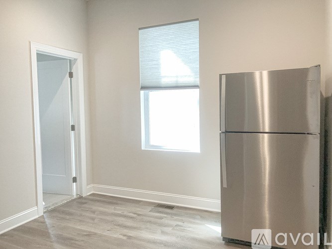 A stainless steel refrigerator sits in a room with a window and a door.
