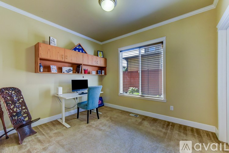 A room with a desk, chair, and a window with blinds.