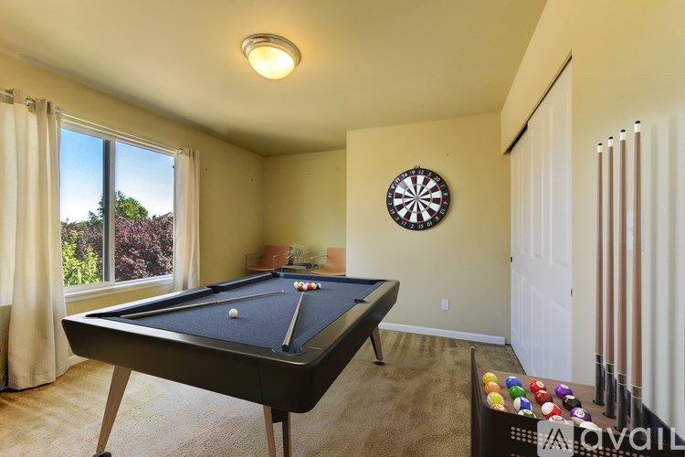 A pool table in a room with a dartboard on the wall.