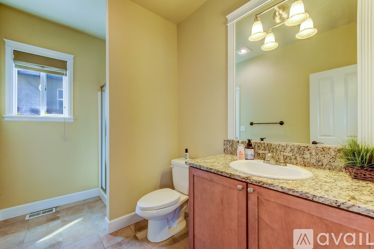 A bathroom with a toilet, sink, and mirror.