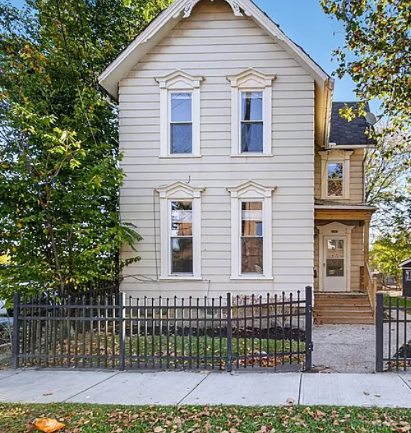 A two-story house with a black fence in front.