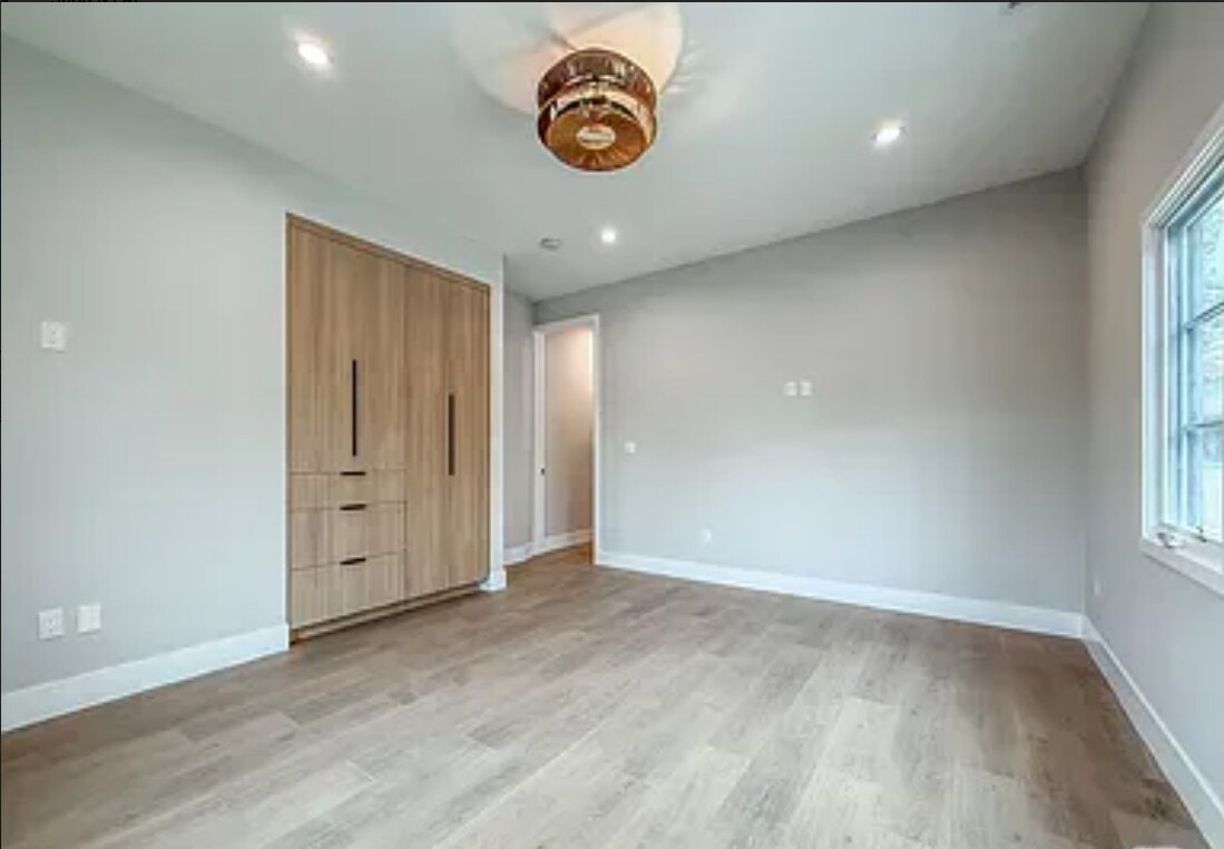 A room with a wooden floor and a wooden cabinet with drawers.