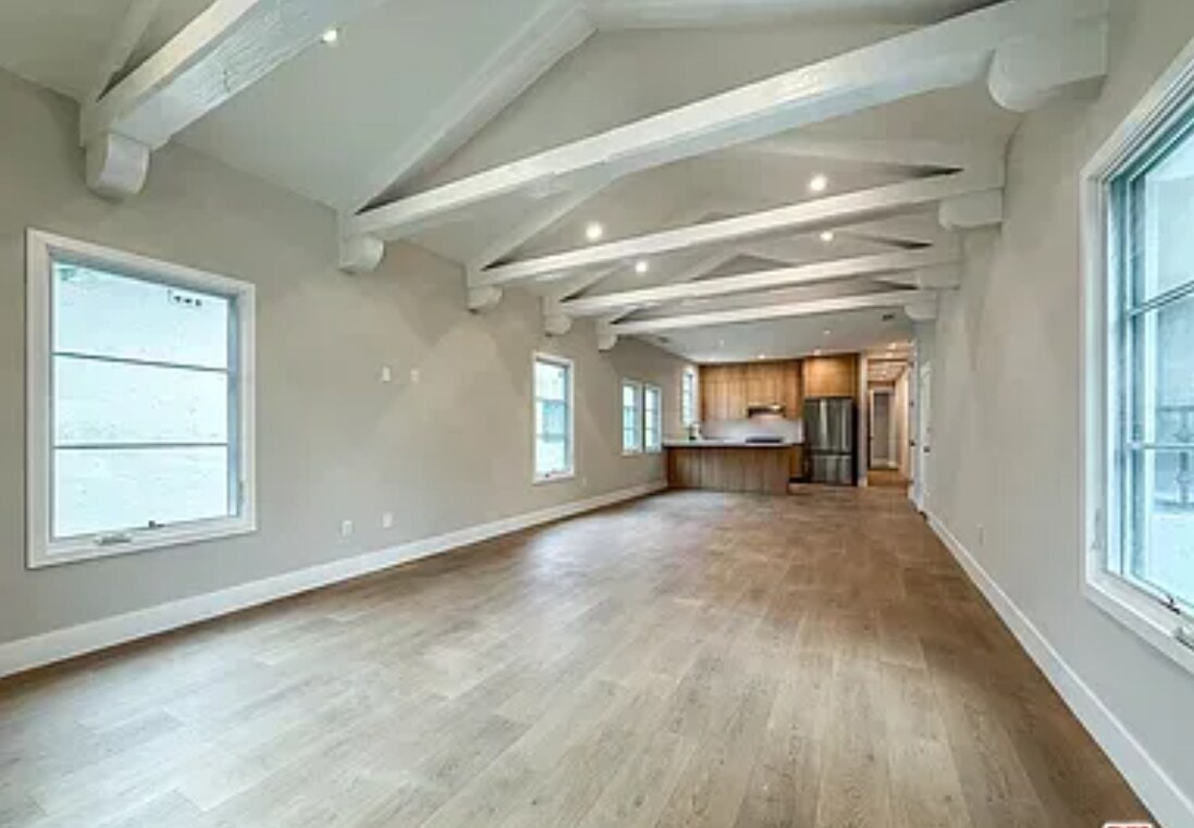 A spacious room with wooden floors and white walls.