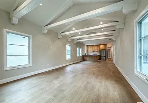 A spacious room with wooden floors and white walls.