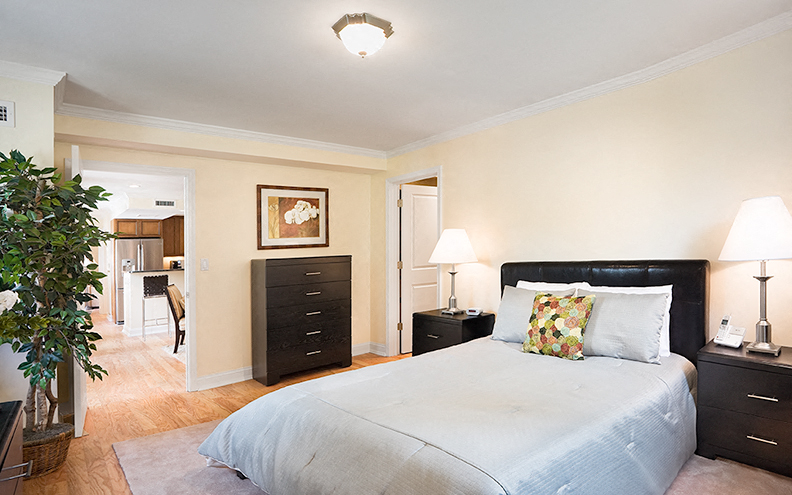 a bedroom with a bed and dressers and a living room