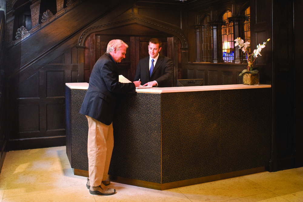 two men shaking hands at a desk in a lobby