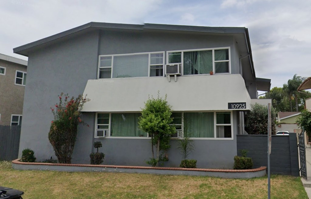 A grey house with a black fence and a mailbox on the front.
