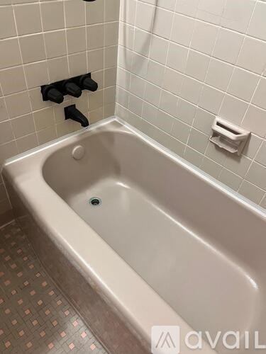 A white bathtub in a bathroom with black handles on the wall.