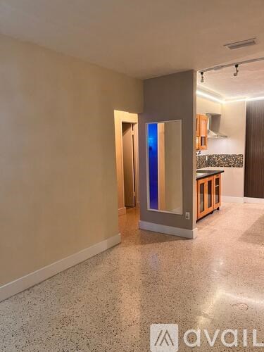 A room with a marble floor and a kitchen area in the background.