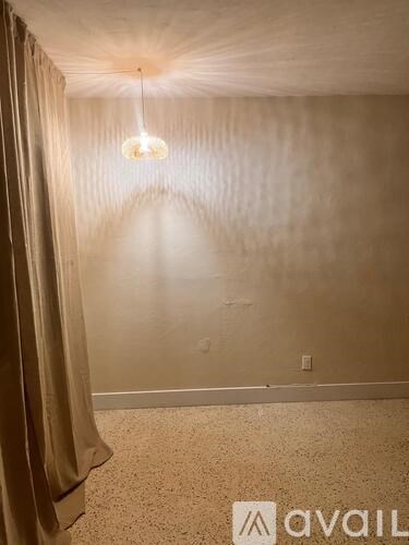 A room with a light hanging from the ceiling and a carpet on the floor.