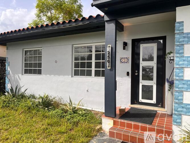 A white house with a black door and a small porch.