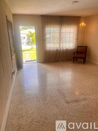 A room with a chair and a window with curtains.