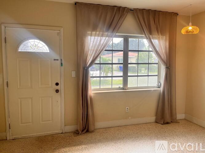 A room with a white door and a window with curtains.