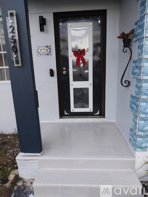 A black door with a glass window and a red bow on it.