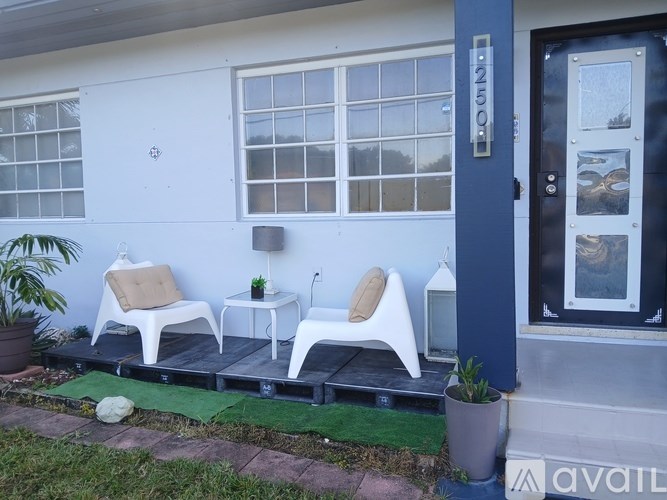 Two white chairs are placed on a wooden platform outside a building.