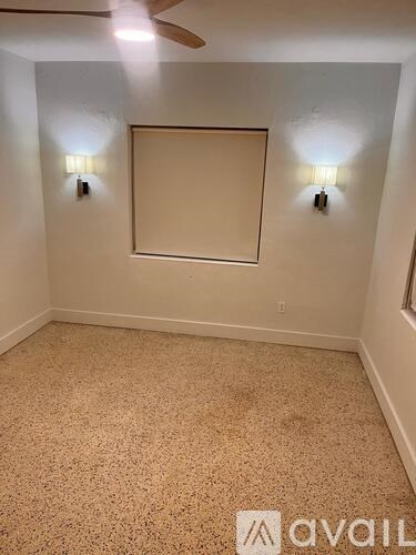 A room with a ceiling fan and two wall lights.