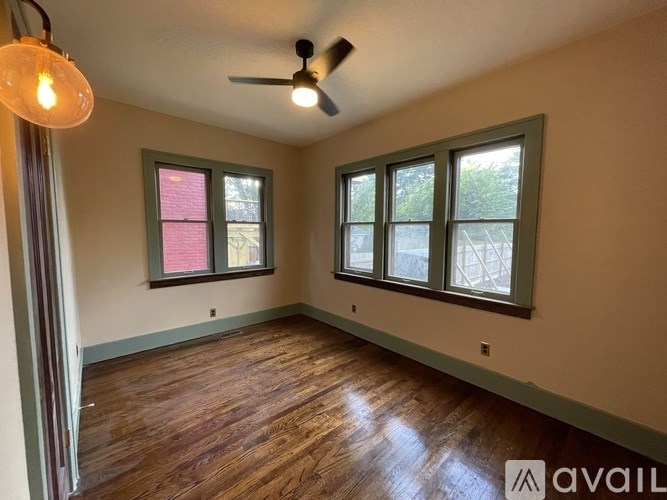 A room with a ceiling fan and two windows.