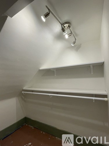 A white wall with a light on it and a shelf.