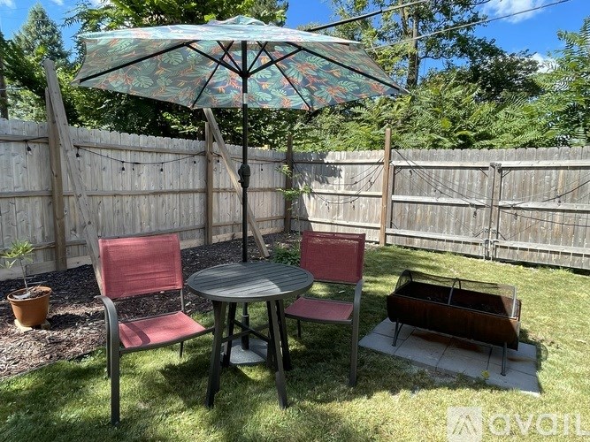A patio with a table, chairs and an umbrella.