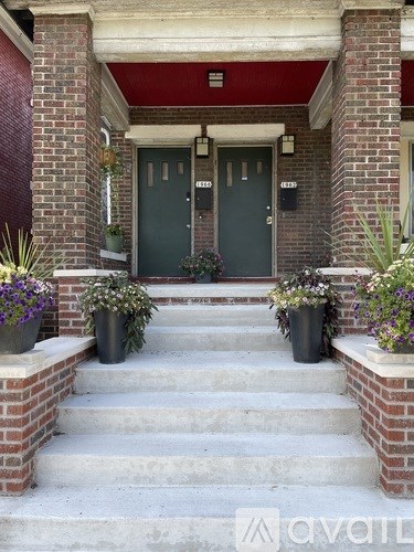 A house entrance with a red brick wall and a green door.
