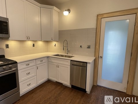A kitchen with white cabinets and a wooden floor.