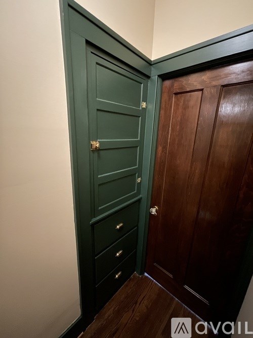 A dark green door with a brass handle and a dark brown door to the right.
