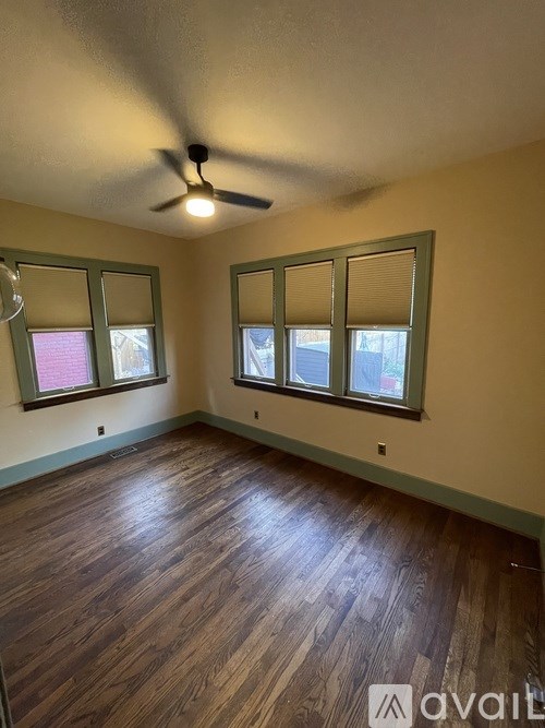 A room with a ceiling fan and wood flooring.