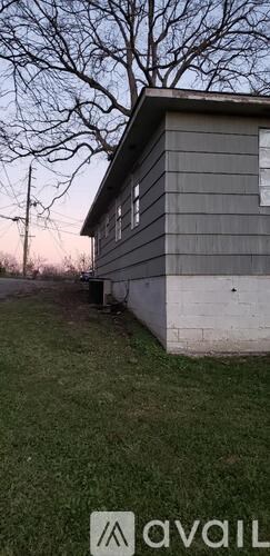 A house with a grey siding and a window is shown.