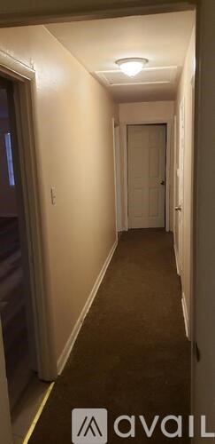 A long hallway with a carpeted floor and white walls.