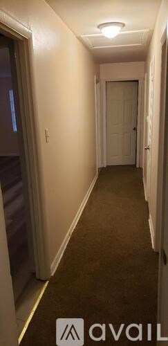 A hallway with a carpeted floor and white walls.