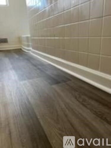 A room with a wooden floor and tiled walls.