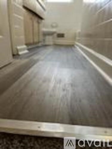 A long hallway with a wooden floor and white walls.