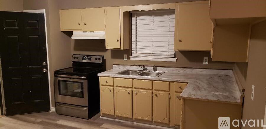 A kitchen with a black stove top oven and a sink with a marble counter top.