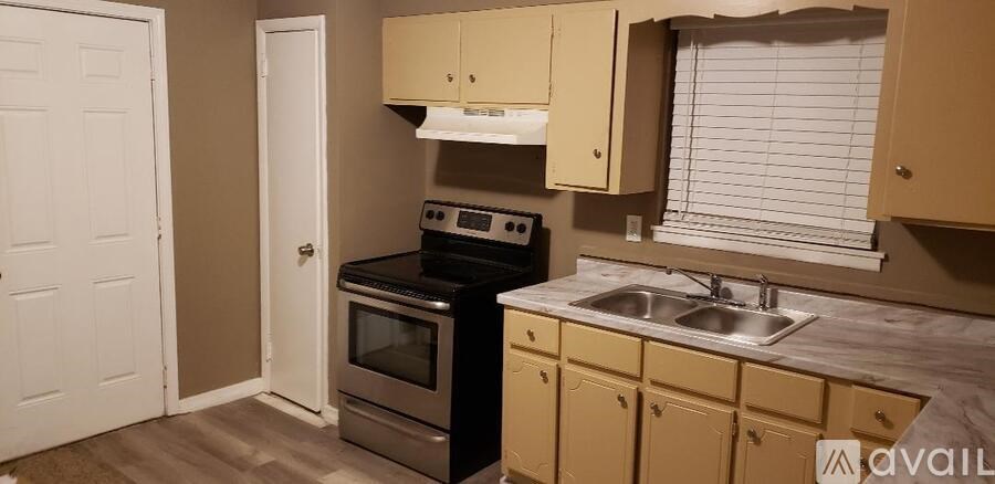 A kitchen with a sink, stove, and cabinets.