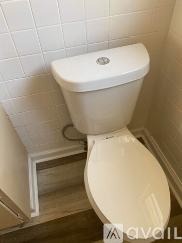 A white toilet in a bathroom with a white tiled wall.