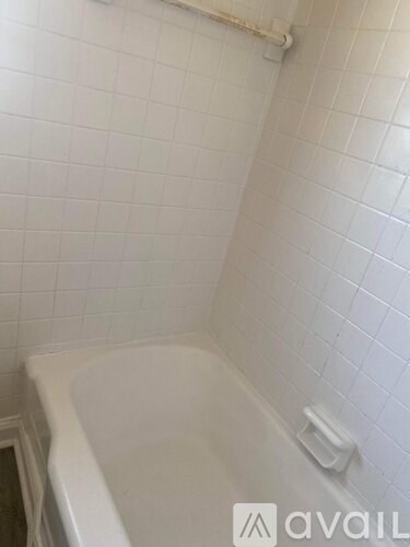 A white bathtub in a bathroom with white tiled walls.